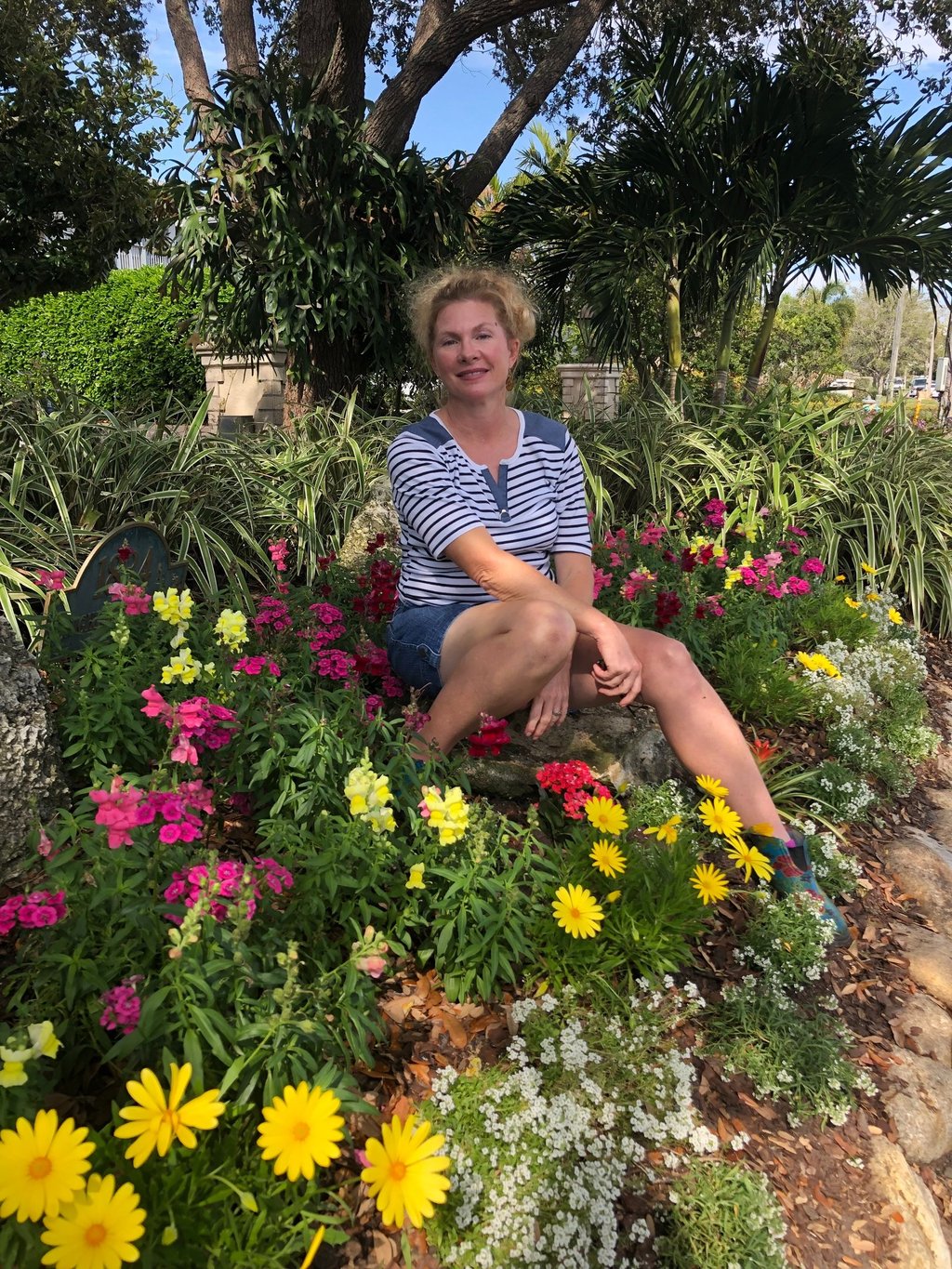 Melanie, founder of Dirt Girls Garden Design, sitting on a bench in a garden